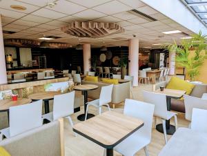 un restaurant avec des tables, des chaises et un comptoir dans l'établissement B&B HOTEL Paris Nord 2 CDG Aéroport, à Roissy-en-France