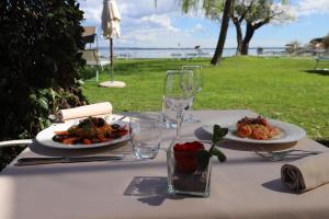 a table with two plates of food and wine glasses at Hotel Fonte Boiola in Sirmione