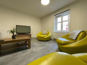 ein Wohnzimmer mit einem gelben Sofa und einem TV in der Unterkunft Central Apartments Opava in Opava