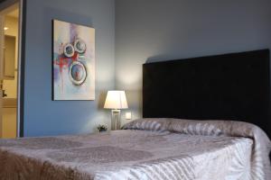 1 dormitorio con 1 cama con una pintura en la pared en Apartamentos La Carmen en Arrecife