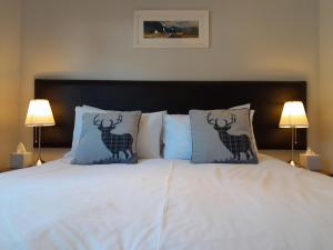 a white bed with two deer pillows on it at Glencoe view lodge in Glencoe