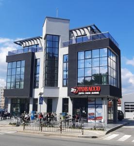 Un bâtiment noir et blanc avec des personnes assises devant lui dans l'établissement Zora, à Blagoevgrad