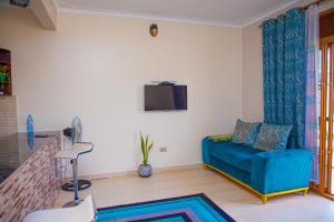 a living room with a blue couch and a tv at J & A VILLAS in Mbale