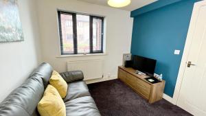 a living room with a leather couch and a television at Cross Court, Stafford by BELL Apartments in Stafford