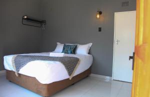um quarto com uma cama com lençóis brancos e almofadas em 4447 Guesthouse em Pimville