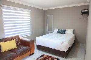 a bedroom with a bed and a couch and a window at 4447 Guesthouse in Pimville