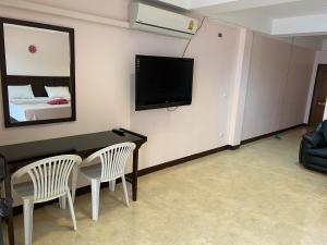 a living room with a table and a tv on a wall at Orient House in Pattaya South