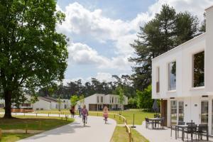 Hechtel-EkselPark Eksel的一群人骑着自行车沿着建筑旁边的人行道骑着