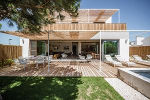 a backyard with a wooden deck with a table and chairs at B.Hostel in Comporta