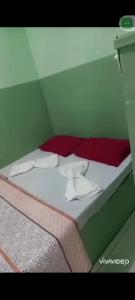 uma cama com lençóis brancos e toalhas em Pousada 146 em Campos dos Goytacazes