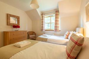 a bedroom with two beds and a dresser and a window at Carn Mhor Lodge in Aviemore