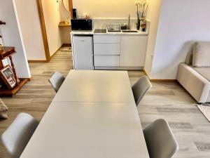 Biały stół i krzesła w pokoju z kuchnią w obiekcie Charming Studio Apartment in Povoa de Varzim w mieście Póvoa de Varzim