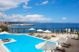 馬蒂的住宿－Ramada by Wyndham , Athens Club Attica Riviera，一个带遮阳伞和椅子的游泳池以及大海