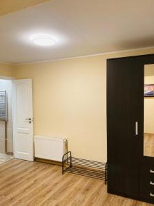an empty room with a black door and wooden floors at Nākotnes street apartaments in Liepāja