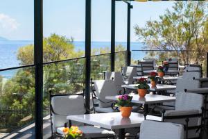 une rangée de tables avec des fleurs sur le balcon dans l'établissement Ramada by Wyndham , Athens Club Attica Riviera, à Mati