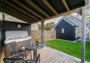 a patio with a table and chairs and a tub at Bedwen in Llanfihangel-geneuʼr-glyn