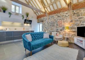 a living room with a blue couch and a stone wall at Bedwen in Llanfihangel-geneuʼr-glyn