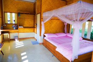 1 dormitorio con cama rosa y dosel en Phonphusang Utopia Farmstay 