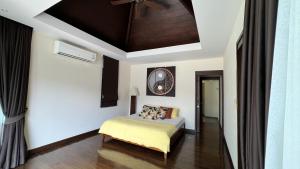 een slaapkamer met een bed en een klok aan de muur bij Plunge Tropic Villas 2 Naiharn in Rawai Beach