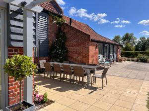 a patio with a table and chairs next to a building at Stackyard Lodge - enchanting 18th Century converted barn in the Waveney Valley in Aldeby