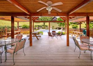 a wooden deck with tables and chairs and a ceiling fan at A Mountain Paradise, 2 Bedrooms, Sleeps 6, Pool Access, Hot Tub, Pool Table in Pigeon Forge