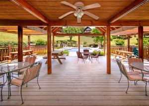 a wooden deck with tables and chairs and a ceiling fan at A Mountain Paradise in Pigeon Forge