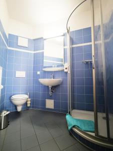 La salle de bains est pourvue de carrelage bleu, de toilettes et d'un lavabo. dans l'établissement StroamCamp Schwedt - a84461, à Schwedt-sur-Oder