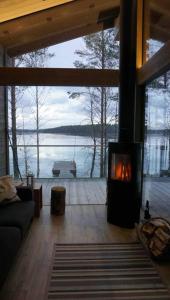 a living room with a fireplace with a view of the water at Luxury guesthouse, beachfront sauna in Jyväskylä