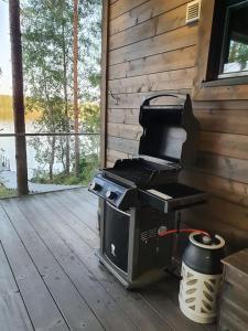 a grill sitting on a wooden deck with a porch at Luxury guesthouse, beachfront sauna in Jyväskylä