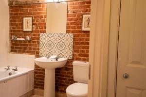 a bathroom with a white toilet and a sink at Stackyard Lodge - enchanting 18th Century converted barn in the Waveney Valley in Aldeby