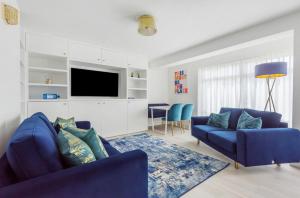 a living room with two blue couches and a tv at Sunny View in East Wittering