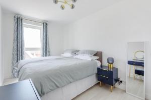 a white bedroom with a large bed and a window at Sunny View in East Wittering