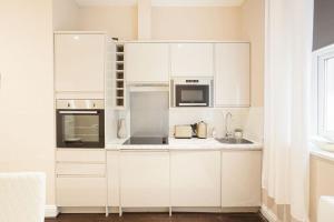 een witte keuken met witte kasten en apparaten bij Beautifully decorated centrally located 2 bed flat in Brighton & Hove