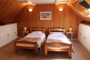 two beds in a room with wooden walls and ceilings at Le Clos De Lascoer in Plumergat