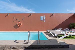 een zwembad met ligstoelen naast een muur bij Villa La Quinta de Vals in Valsequillo