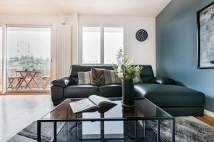 uma sala de estar com um sofá de couro preto e uma mesa em Le Grand Fauriel 100m 6 places em Saint-Étienne