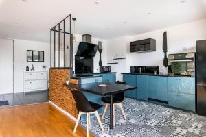 uma cozinha com armários azuis e uma mesa e cadeiras pretas em Le Grand Fauriel 100m 6 places em Saint-Étienne