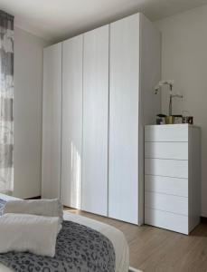 Residence Outlet Vivaldi في نوفينتا دي بْيافي: غرفة نوم مع سرير وخزانة بيضاء كبيرة