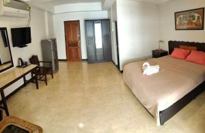 a bedroom with a bed and a desk and a television at Orient House in Pattaya South
