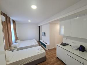 um quarto branco com 2 camas e um espelho em Apartman Casa em Trebinje