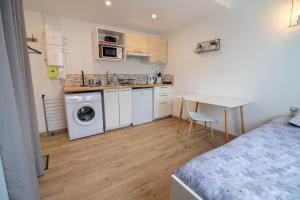a bedroom with a bed and a kitchen with a washing machine at Studio duplex, proche université in Montbéliard