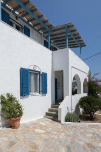a white house with blue shutters and a porch at Summer House - Finikas Syros in Víssa