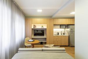 a bedroom with two beds and a table and a kitchen at Charlie JP Redenção Cidade Baixa in Porto Alegre