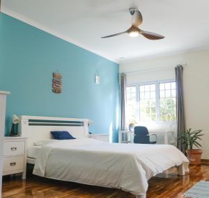 a bedroom with a white bed and a blue wall at LAVA Açores Coliving in Ribeira Grande