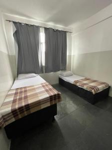 2 camas individuales en una habitación con ventana en Pousada 146 en Campos dos Goytacazes