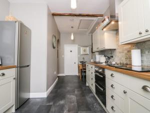 a kitchen with white cabinets and black appliances at Cartmel Flat in Grange Over Sands