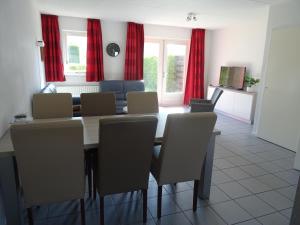 a dining room with red curtains and a table and chairs at Kustverhuur, Vakantiepark Fort Soleil 26 in Breskens