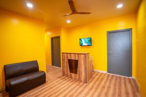 a room with yellow walls and a chair and a door at Yellow Bells Signature HITEC City in Hyderabad +26 photos
