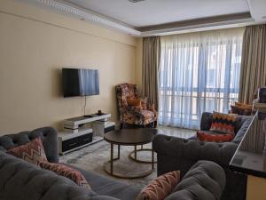 a living room with couches and a tv and a table at Bliss haven gardens two bedroom apartment in Nairobi