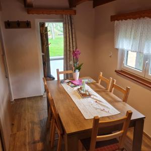 une table à manger en bois avec des chaises et une fenêtre dans l'établissement Gozdarjeva hiška M&K, à Dobrovnik